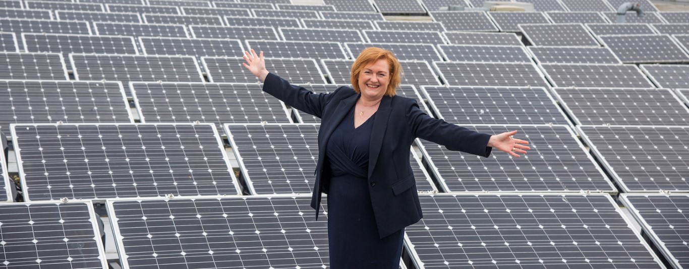 Angela Cox standing next to solar panels
