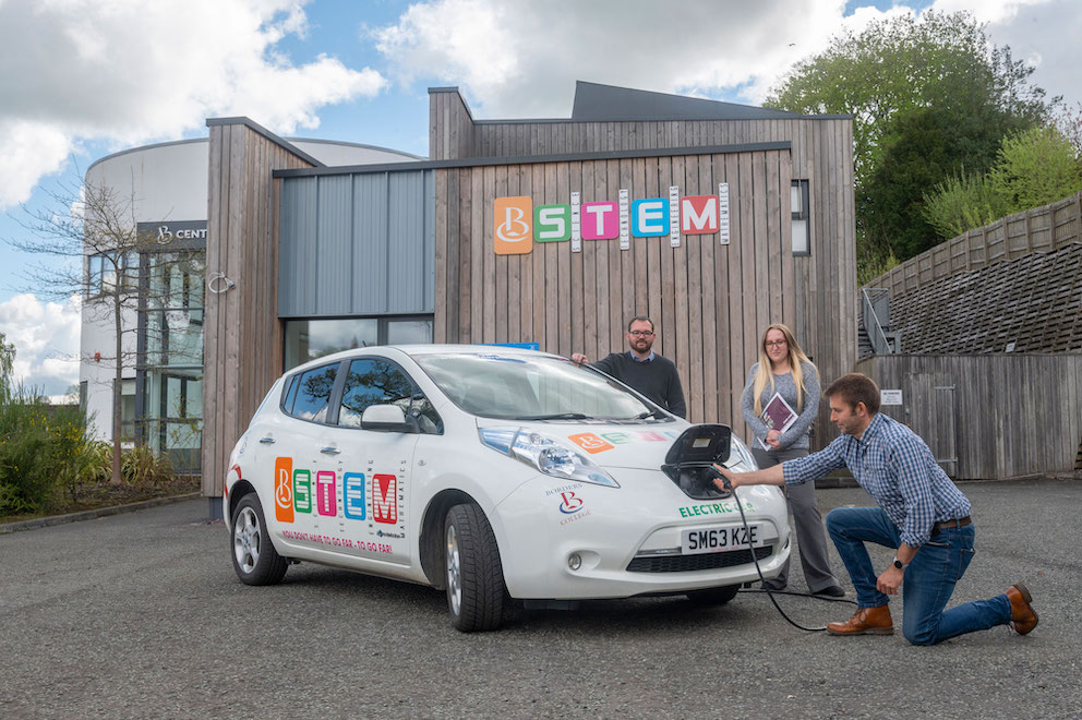 staff standing next to electric car