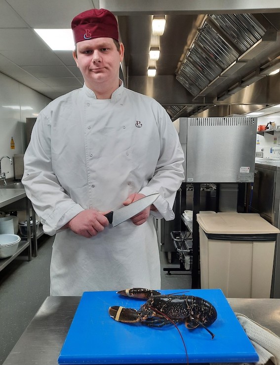 Student chef standing in kitchen with cooking knife