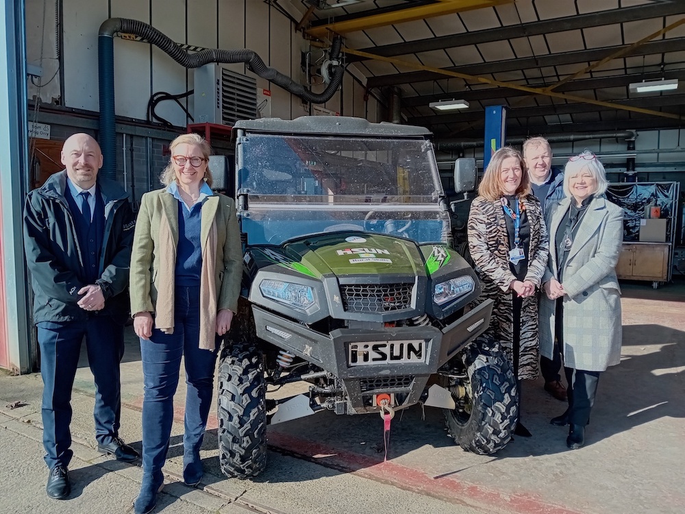 Group of people standing next to an electric ATV