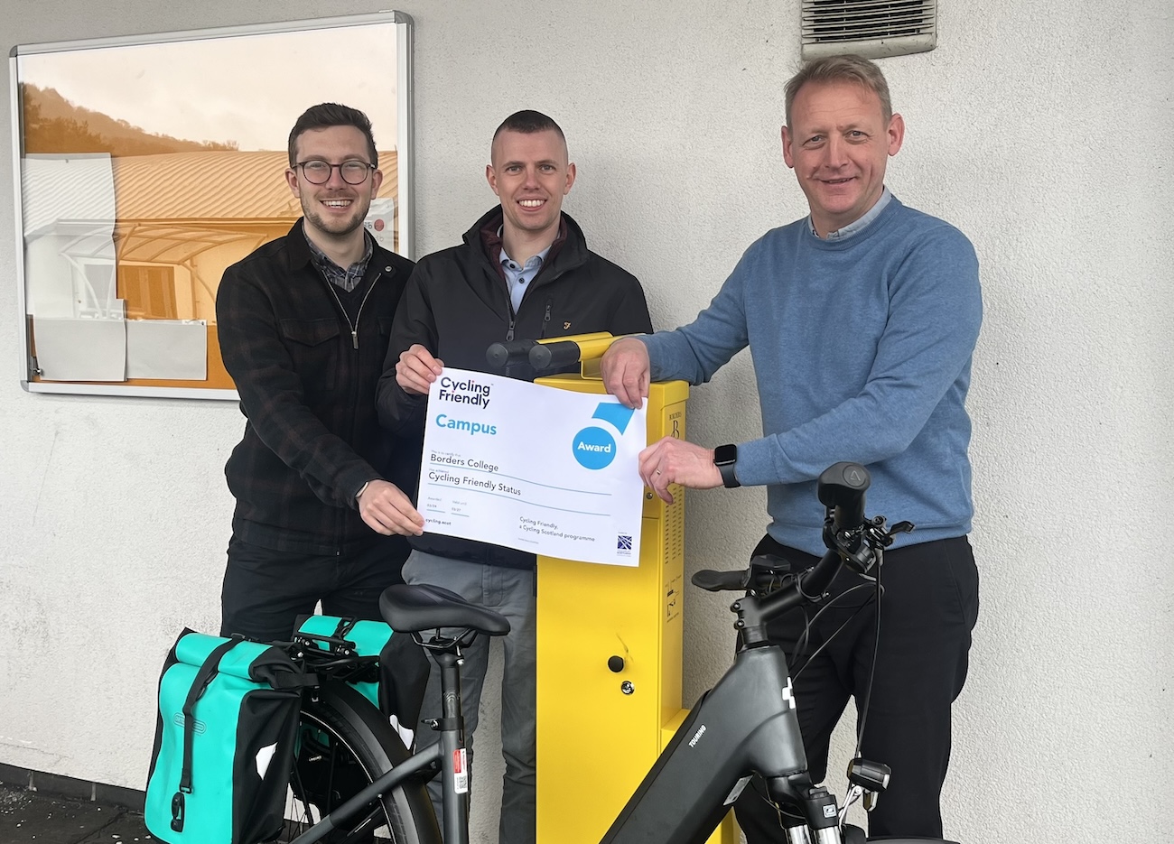 Three people pictured holding a certificate and standing with biking accessories.