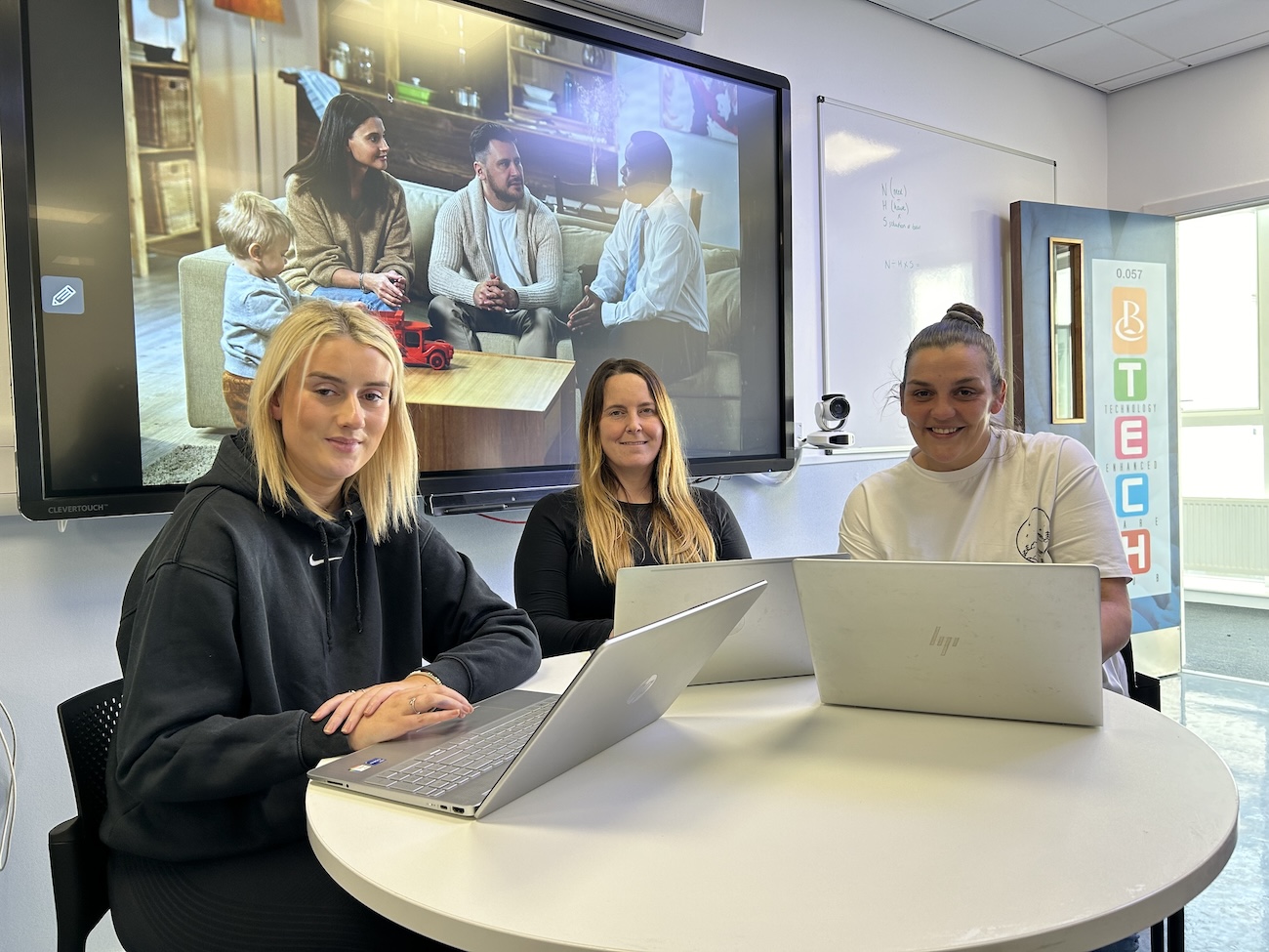 Group of students sitting at a desk with laptops