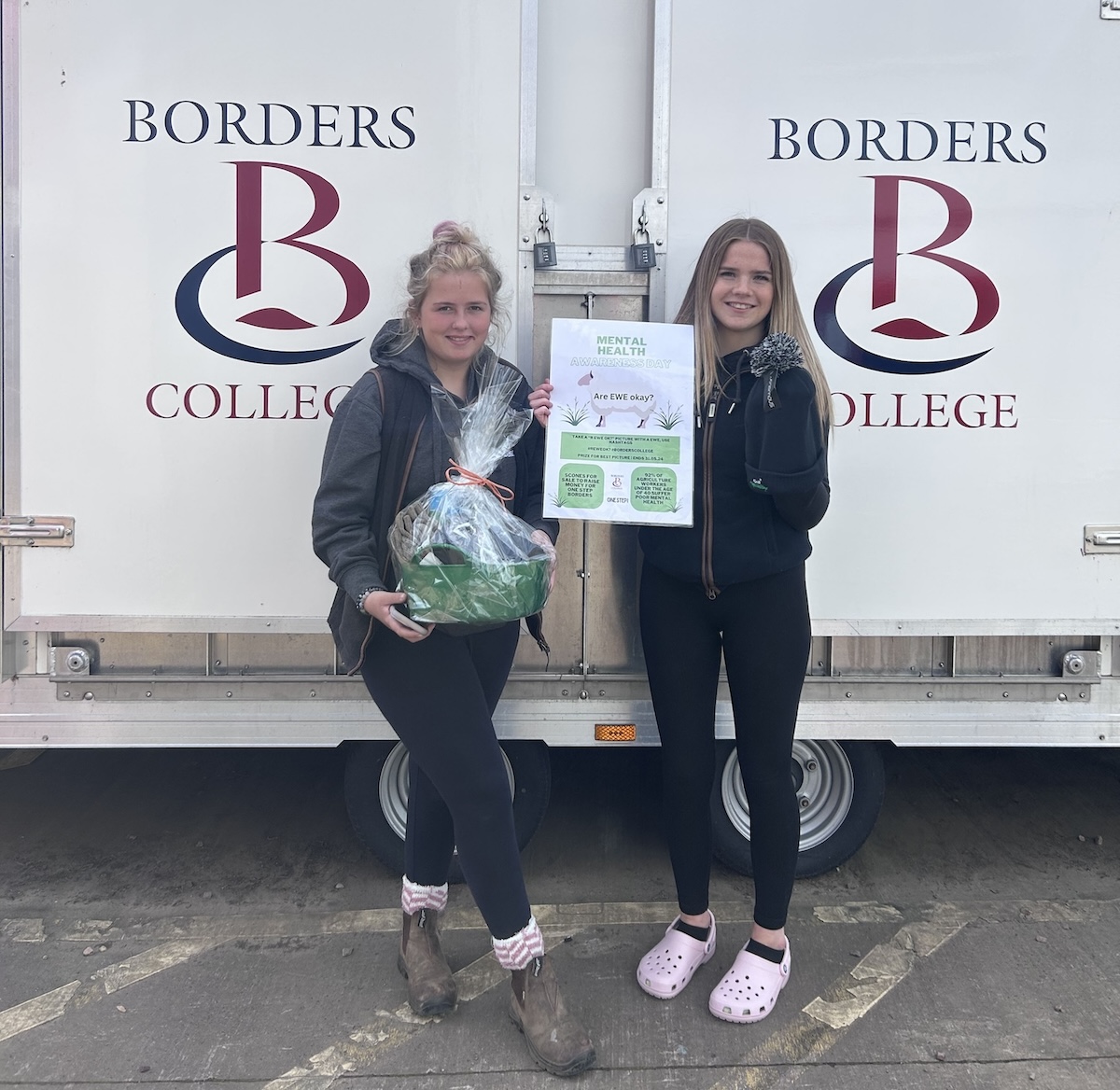 Two students pictured holding a certificate and hamper