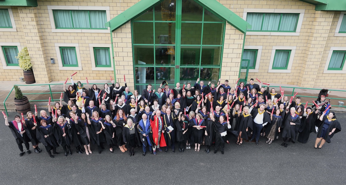 Photograph of the 2025 Graduation group standing outside a building. Taken from an elevated position