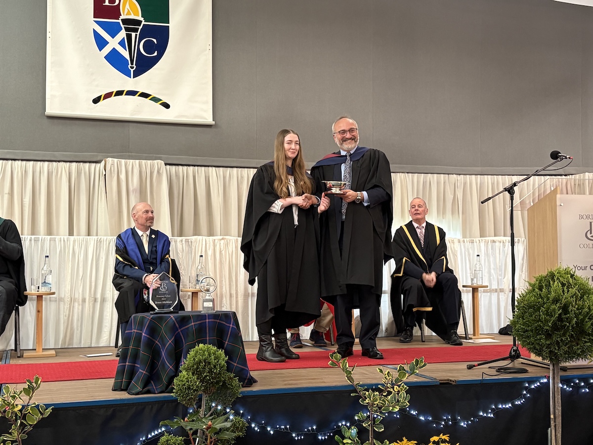 Photo showing a student being presented an award on stag at a graduation ceremony.