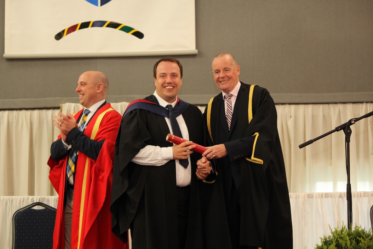 A student being presented his award by a Borders College staff member on stage.