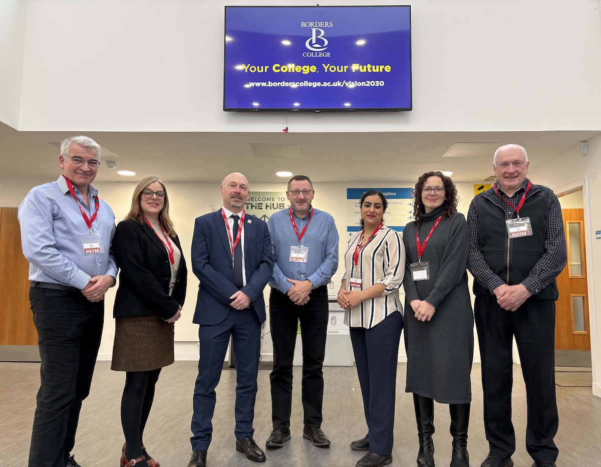 Group photo of seven people standing in a college reception area.