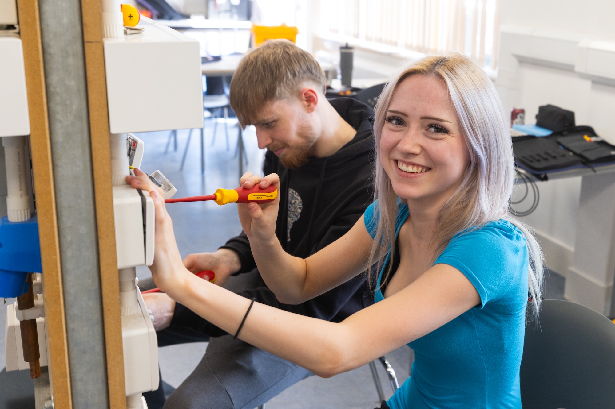 Picture of two students working on an electric board in a classroom setting