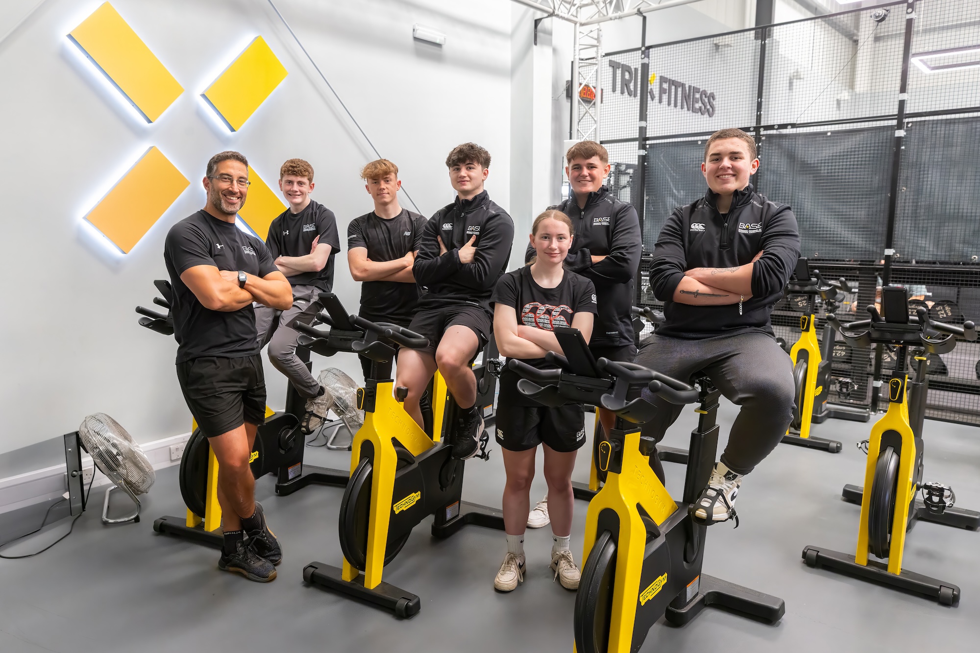 Group of sport students sitting on static bikes inside a gym