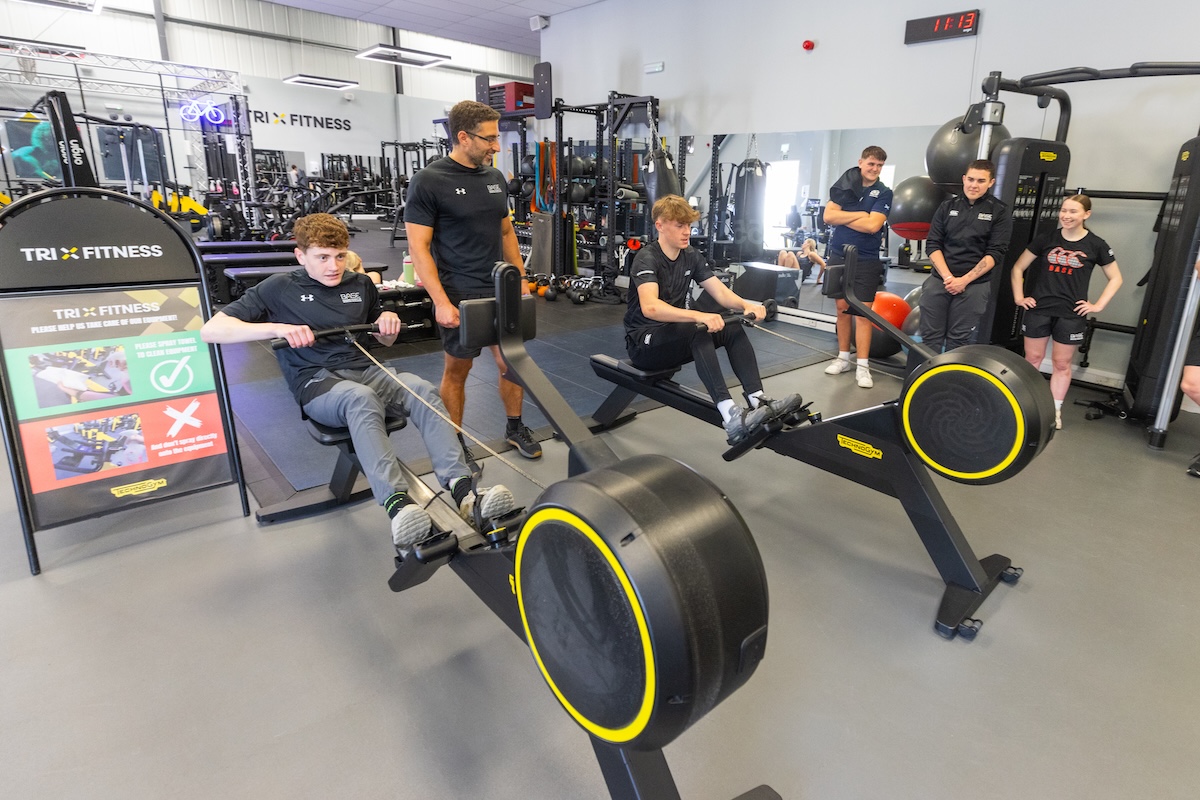 Staff and student using rowing machines in a gym setting