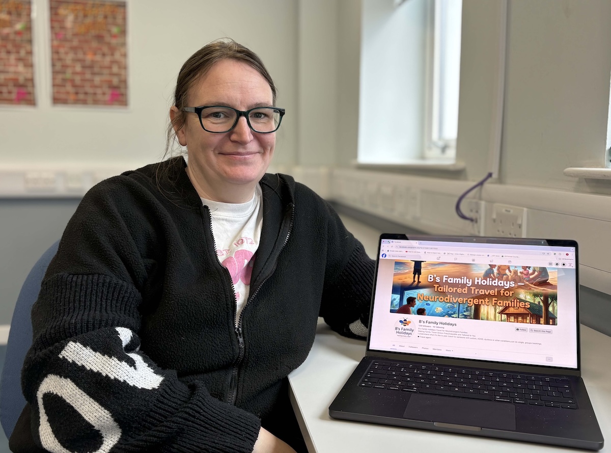 Photo of Bernadette Oliver sitting in a classroom setting with a laptop by her side.