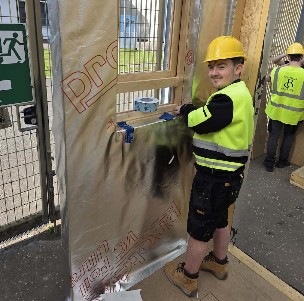 Photo of a carpentry student working with membrane materials on a construction project