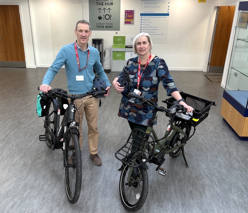 2 people standing at Borders College reception alongside pedal bikes