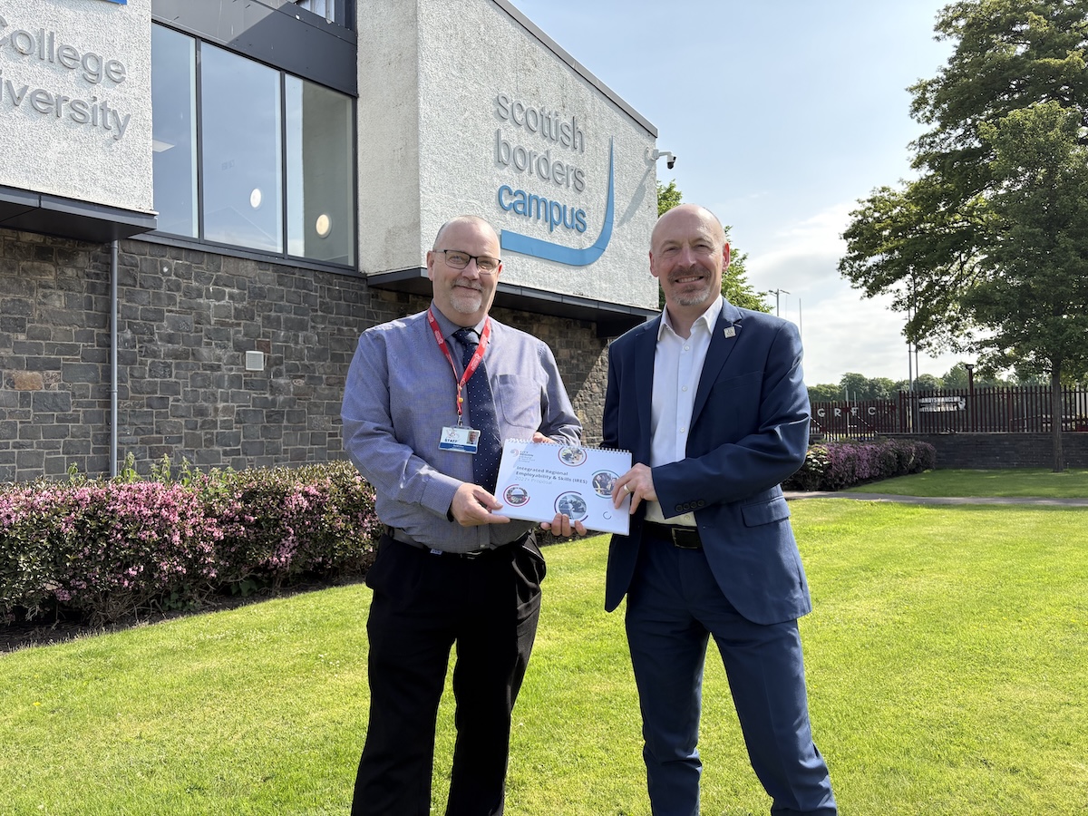 Photograph showing two people standing outside the Scottish Borders Campus holding a document