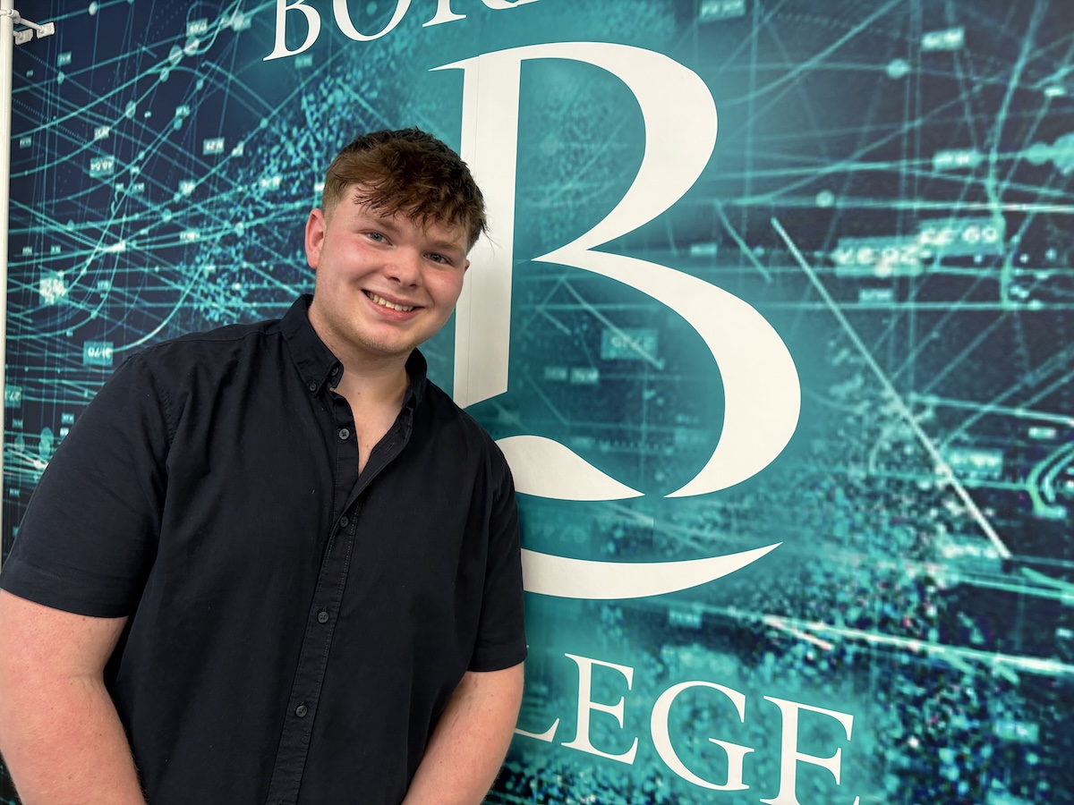 Photo of Mitchel Robertson standing in front of a Borders College Cyber Security graphic