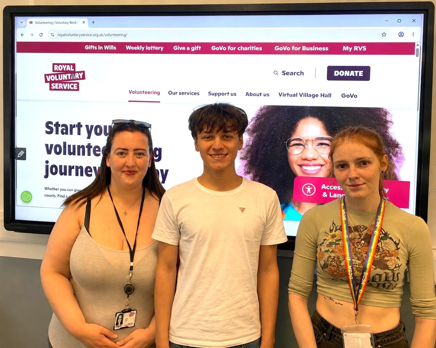 Photograph of three students standing in front of a digital screen