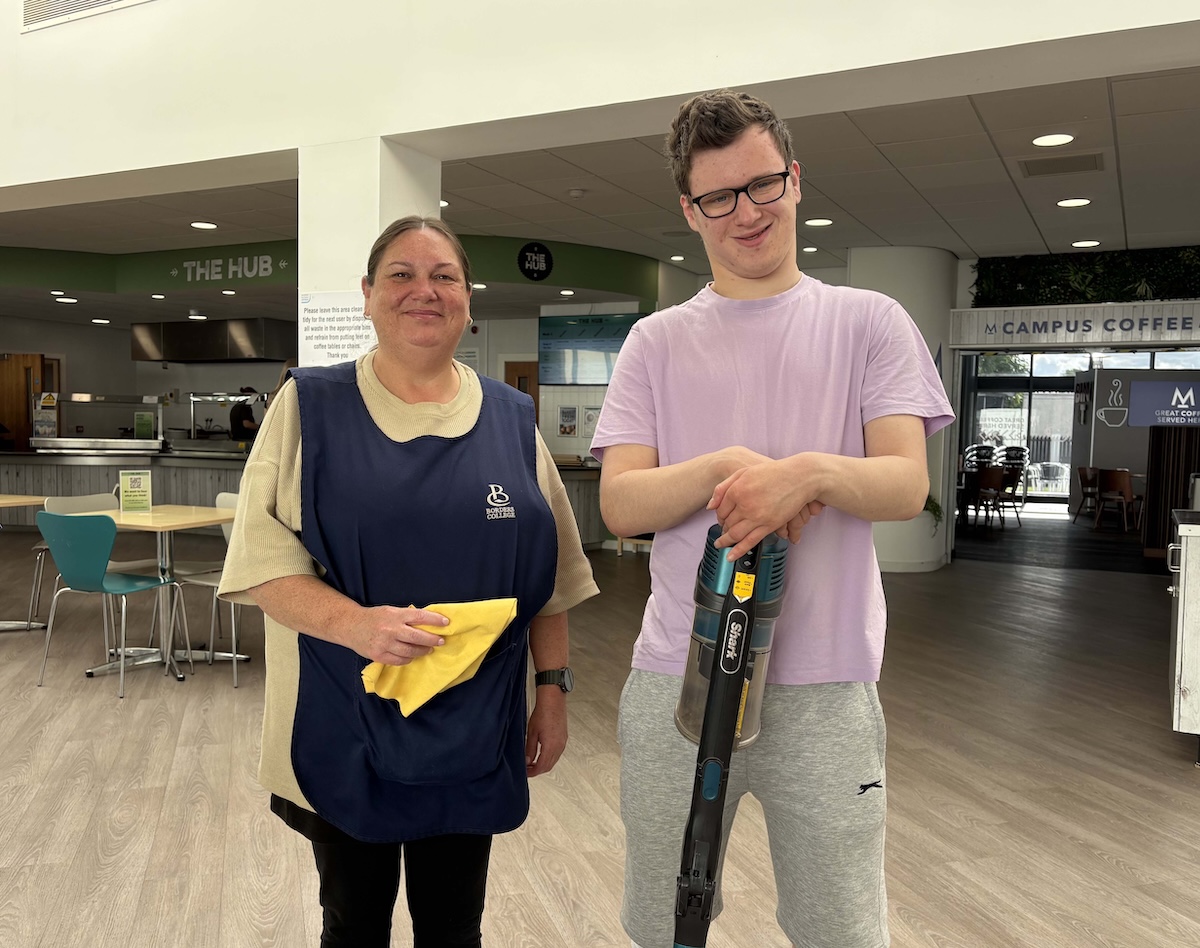 Photo of two people standing in a student union with cleaning equipment in hand