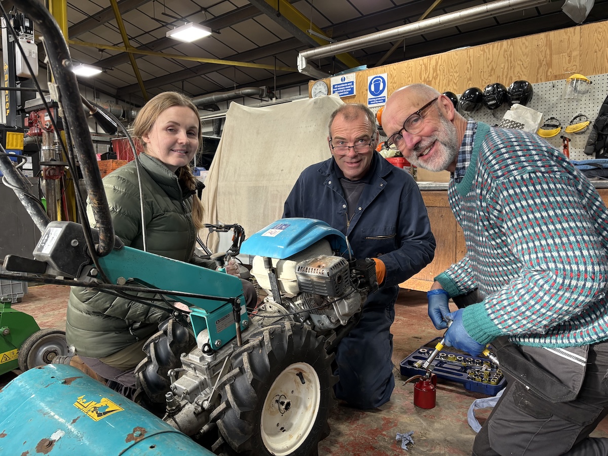 Photo of three people repairing a grass cutter