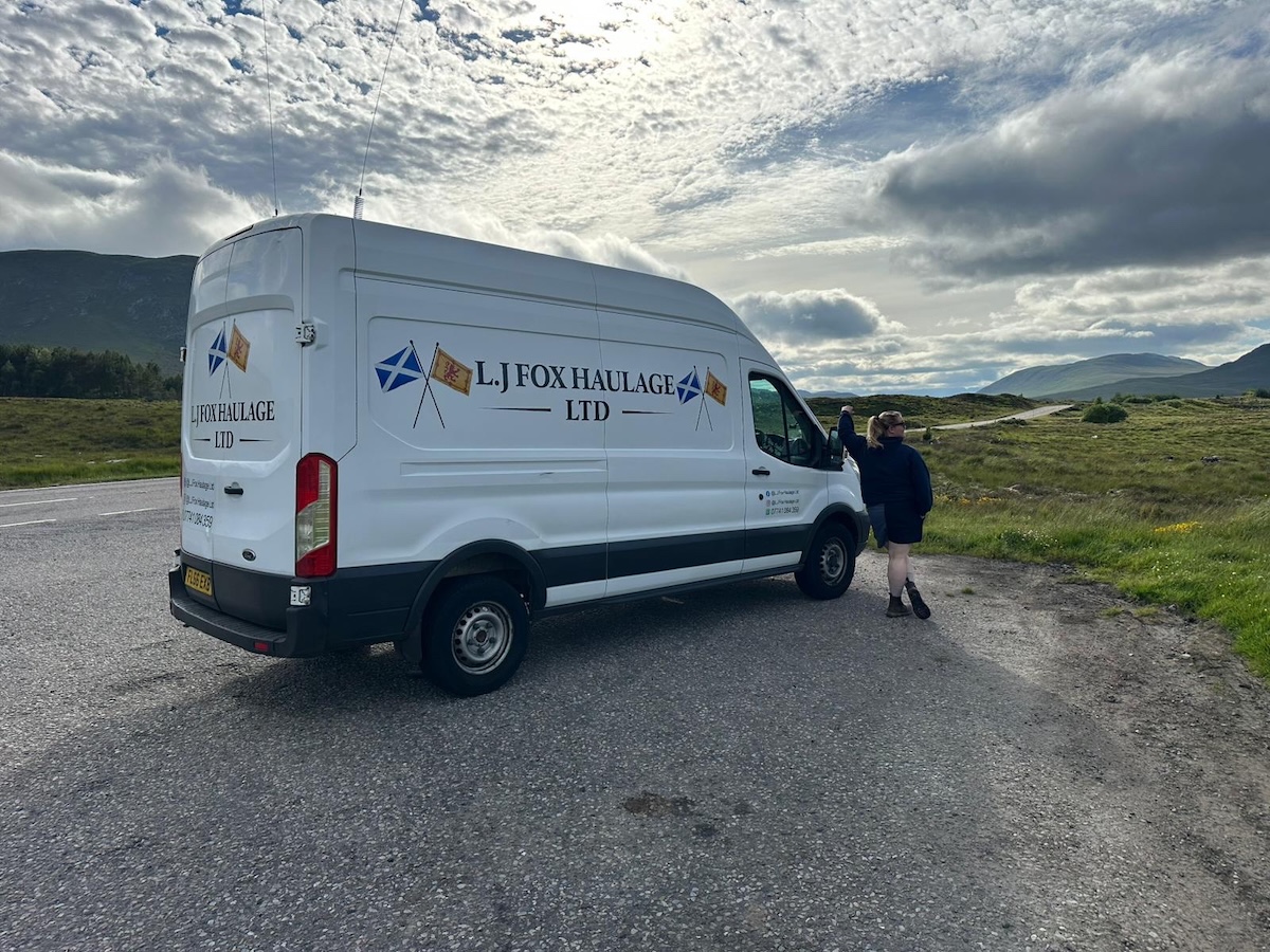 photo of a van parked an an outdoor setting. A person is standing next to the van