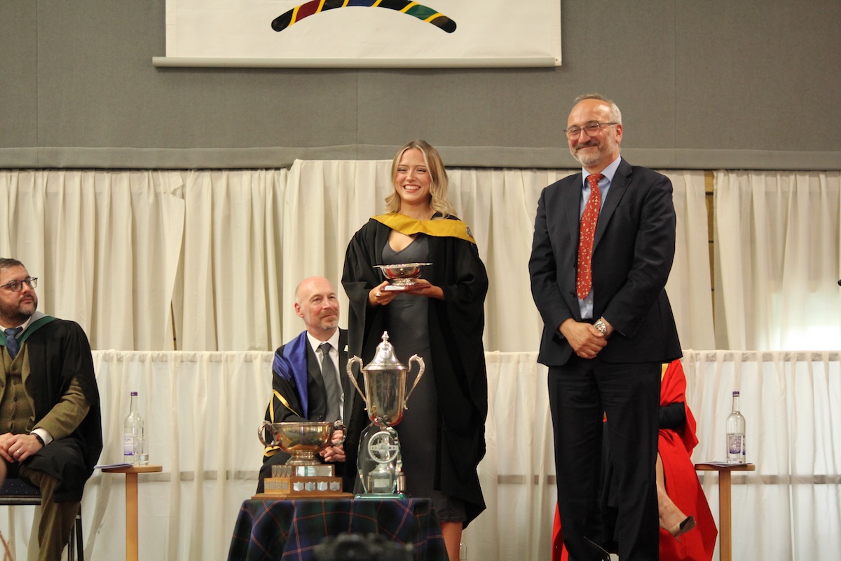 Photo of a student being presented an award on stage at the borders college graduation