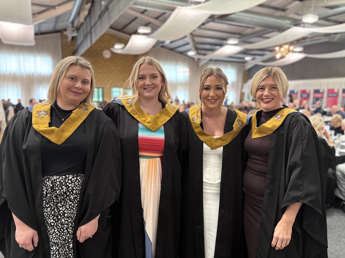 Four graduates standing inside the borders events centre